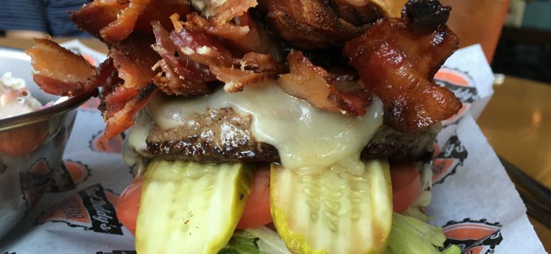 Mouthwatering burger topped with bacon, cheese, tomato, and pickles.