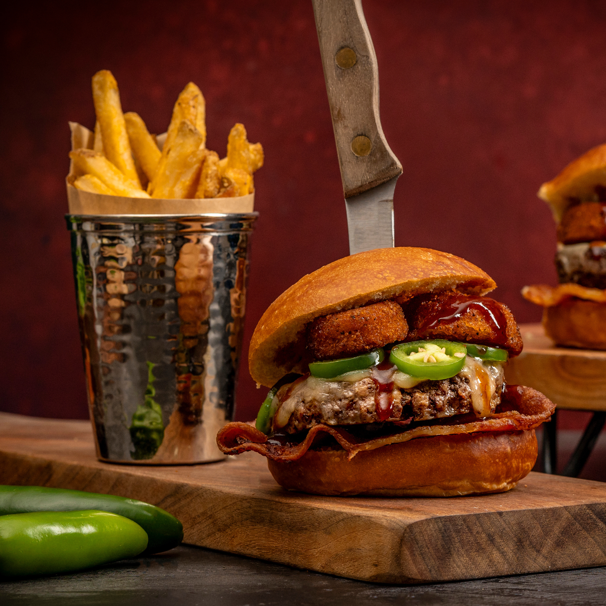 the rodeo burger made from schweid and sons the ribeye blend burgers topped with onion rings, barbecue sauce, sliced jalapenos, bacon, and white cheddar cheese