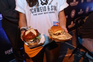girl in a white tshirt holding two burgers