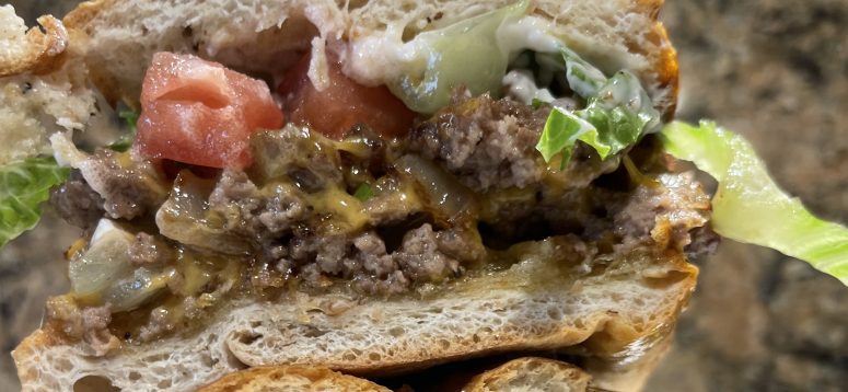 Chopped cheese sandwich topped with tomatoes and lettuce