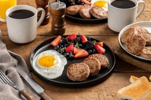 sausage patties plated with sunny side up eggs and fruit