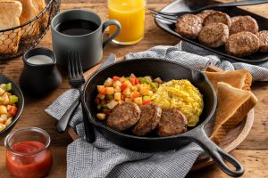Pork Sausage breakfast patties in skillet with eggs and veggies