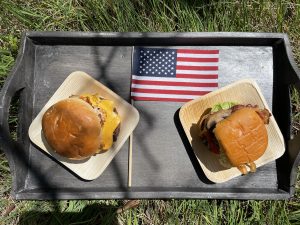 two burgers on tray with an american flag.