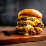 The cheesy, gooey Burger patties stacked on a wooden board