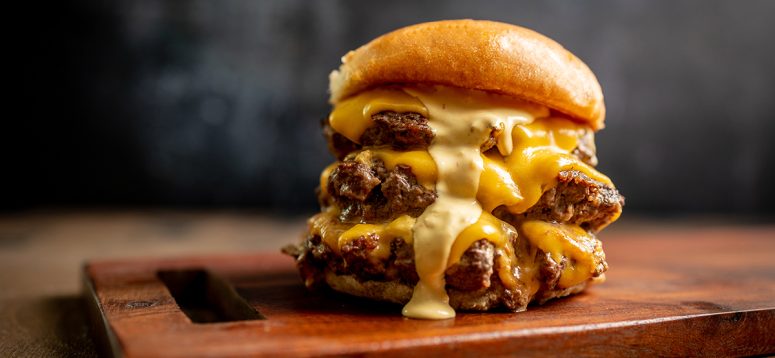 The cheesy, gooey Burger patties stacked on a wooden board