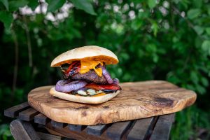 Burger topped with bright veggies taken on a wooden plate. Summer Garden Ingredients