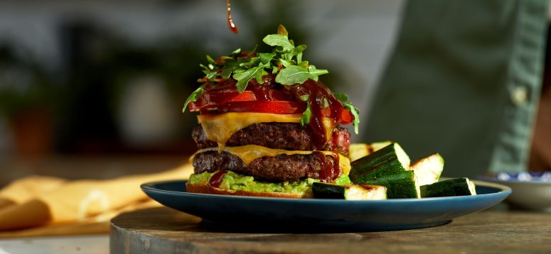Double Stacked Burger with spoon pouring sauce