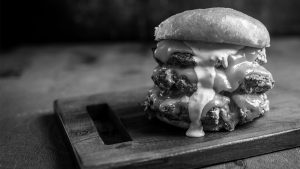 Triple stacked Burger on a wooden cutting board and in black and white