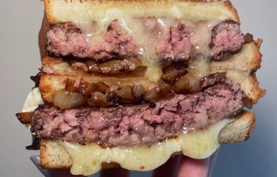A cheesy patty melt that is cut in half and stacked on top of eachother.