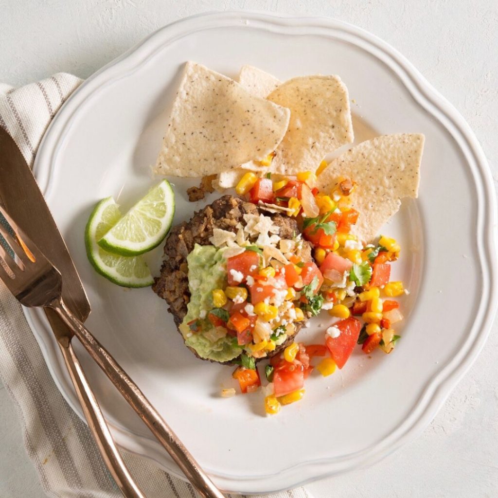 avocado burger topped with corn, tomatoes and guac