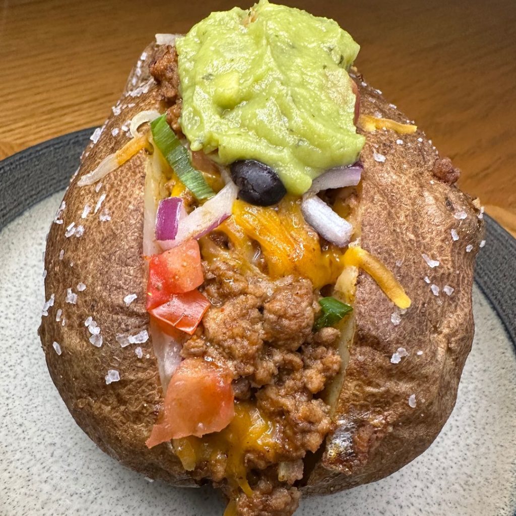 taco stuffed baked potato with Schweid and sons ground beef, guac, cheese, tomatoes, and onions