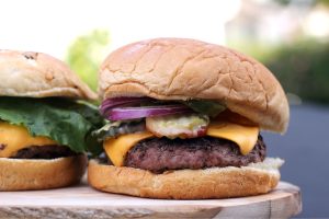 burger topped with cheese and onions. learn what goes into making the perfect burger with schweid and sons