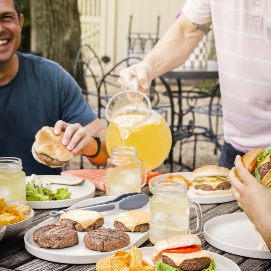 people eating cheeseburgers together outsite