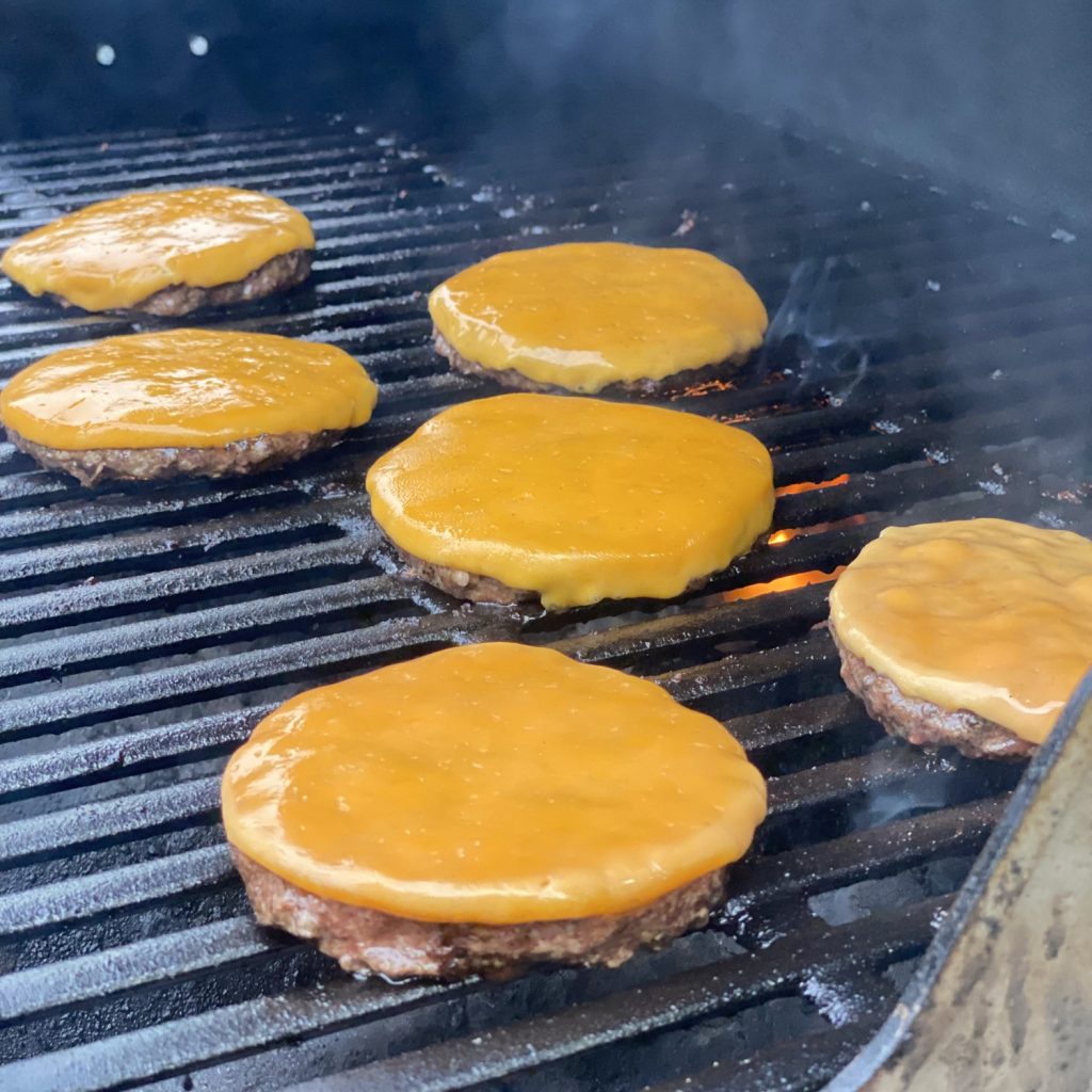 schweid and sons burgers on a grill with melted american cheese