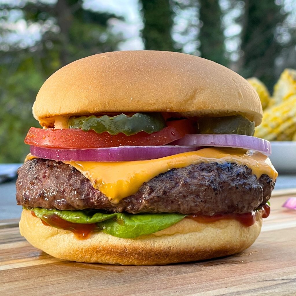 Classic schweid and sons burger topped with american cheese, red onion, tomato, pickles, lettuce, and ketchup all on a toasted bun