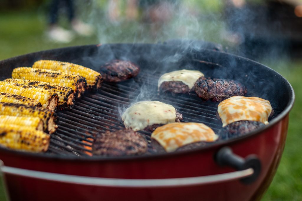 schweid and sons burgers with melted cheese on a grill with charred corn