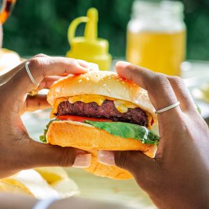 Schweid & Sons Burger on a sesame seed bun topped with melted cheese, lettuce and tomato