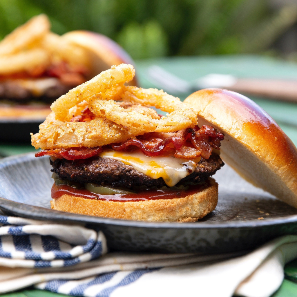 schweid and sons bourbon bacon barbecue cheeseburger topped with cheese, bacon, onion rings, pickles, and barbecue sauce